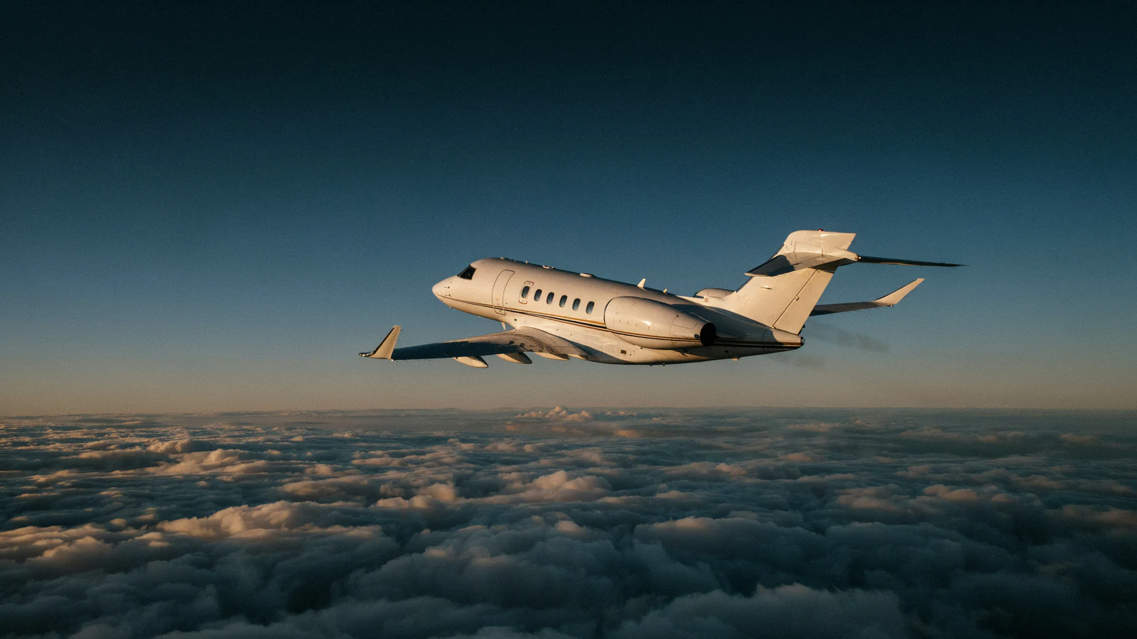 A business jet in flight above the clouds at sunset